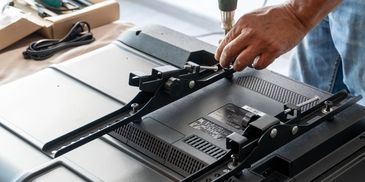 Hand installing a mount bracket on the back of a flat-screen TV.