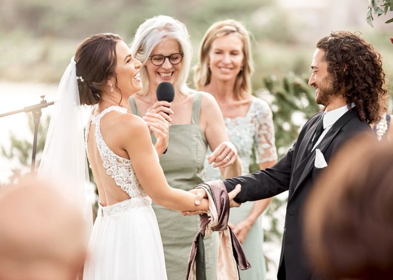 Mother at a wedding doing a speech for bride and groom, smiling and laughing together. Wedding official, celebration and love with family at the ceremony outdoors. Marriage, romance and happy couple
