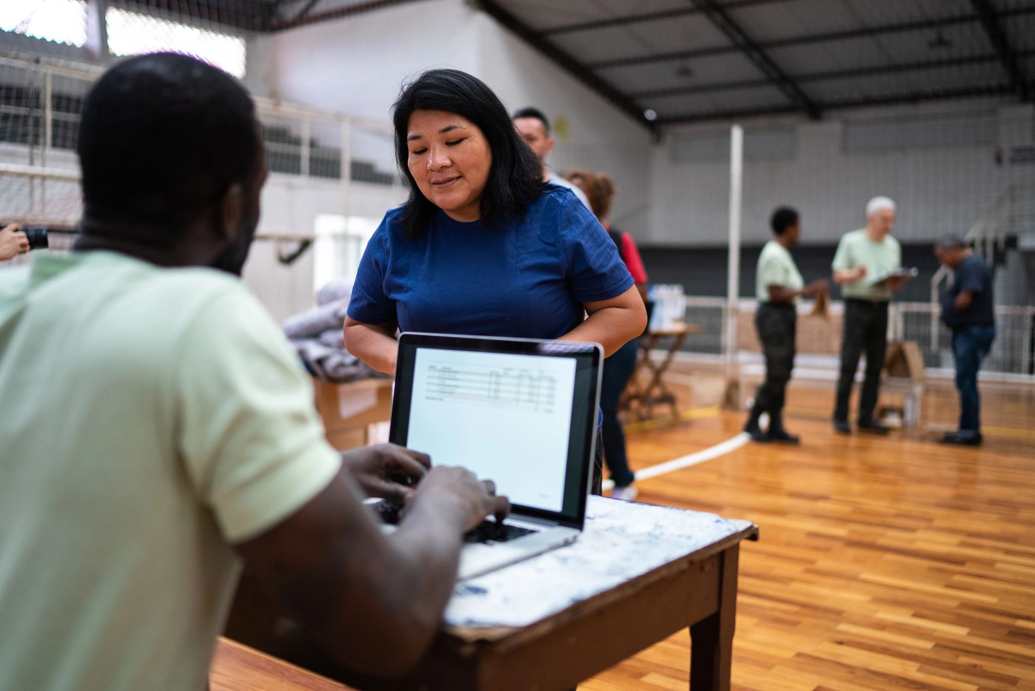 Woman interacting with man using laptop in gymnasium.