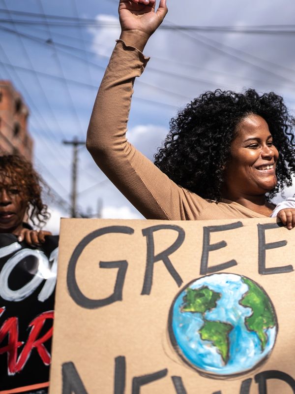 People hold signs advocating for the Green New Deal during a protest.