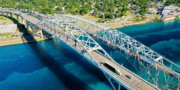 A large steel bridge over blue water with vehicles crossing.