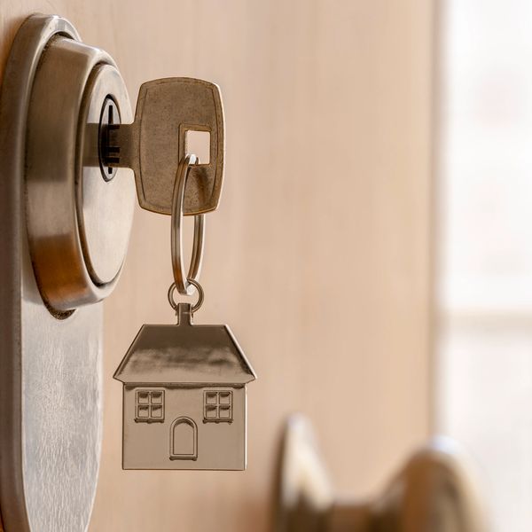 Key with house-shaped keychain in lock.