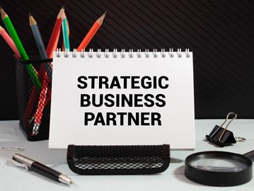 Desk setup with a sign reading 'Strategic Business Partner' and office supplies.