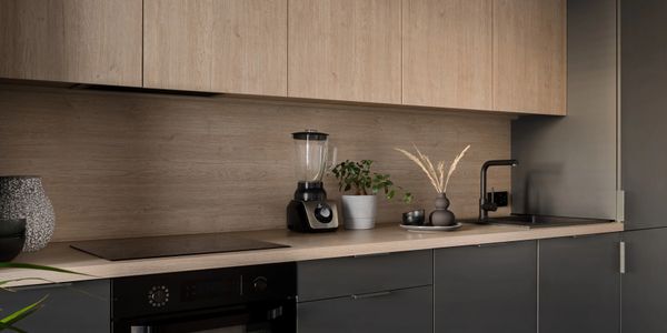 Modern kitchen countertop with blender, plants, and black faucet.