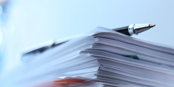 A pen resting on a stack of papers.