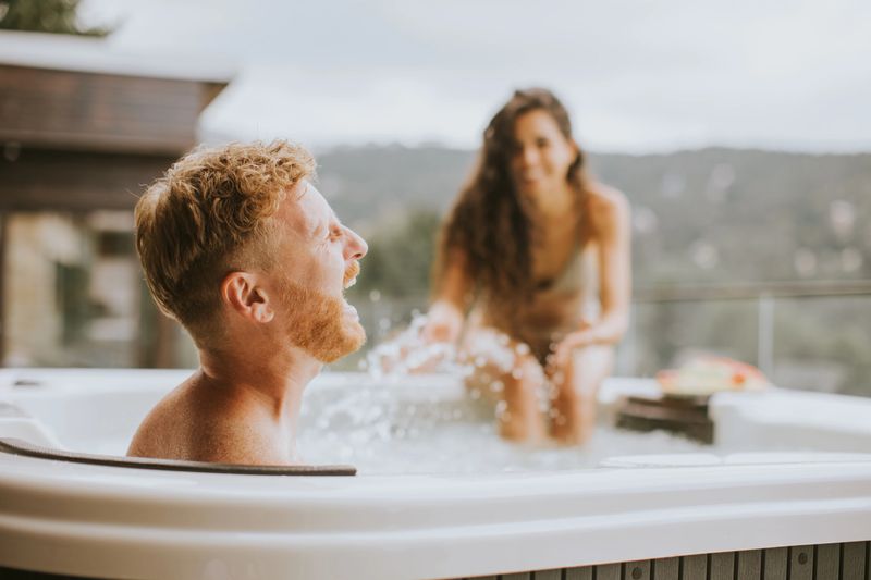 Attractive young couple enjoying in outdoor hot tub on vacation