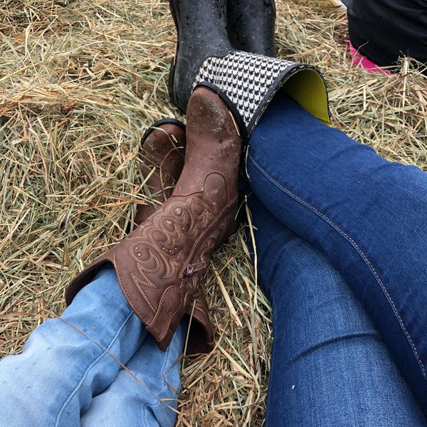 Two people wearing boots resting on hay.