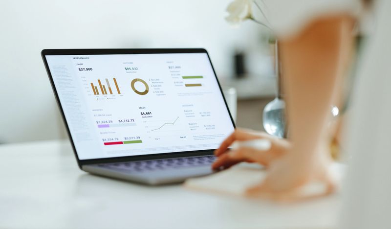 Close up photo of woman hands typing business report on a laptop keyboard at office desk.