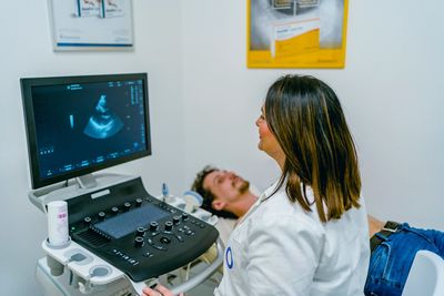 Medical professional reviewing ultrasound report forms with device and notes.