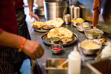 Traditional Indian thali with curries, rice, naan in metal dishes

