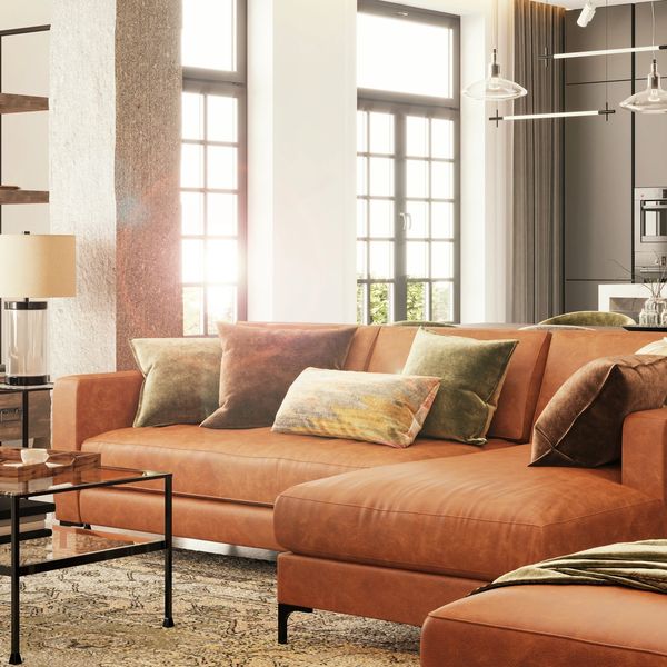 Sunlit modern living room with leather sofa and glass coffee table.