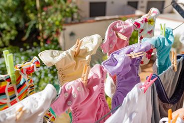 Colorful cloth diapers hanging on a clothesline outdoors.