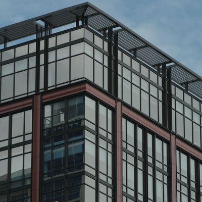 Modern building with large glass windows and metal framework under a clear sky.