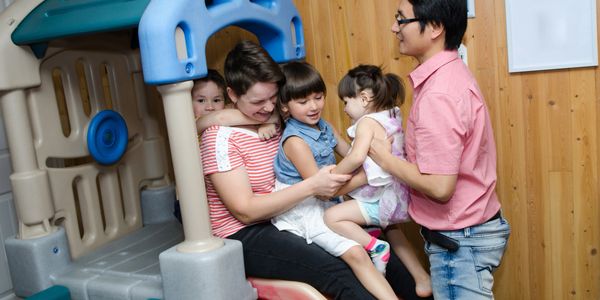 Family enjoying playtime on an indoor plastic slide together.