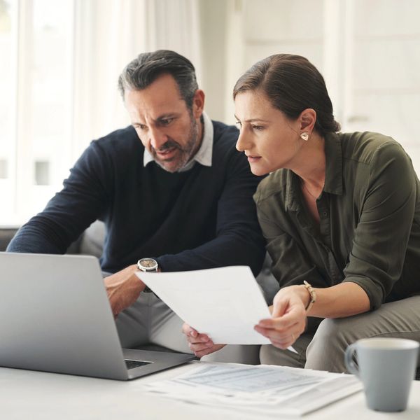 A couple reviews documents and uses a laptop together at home.
