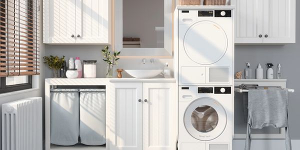 Bright, modern laundry room with stacked washer and dryer and white cabinetry.