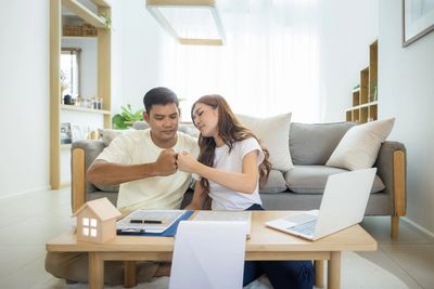 Couple planning finances together at home with documents and laptop.