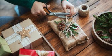 Person wrapping a gift with natural decorations.