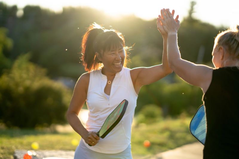 Two pickle ball players celebrate a team point during a game.