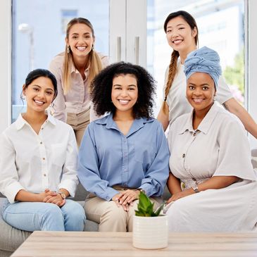 Group of five diverse women smiling indoors.