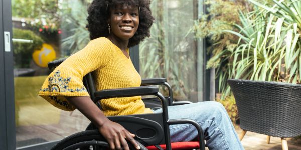 Smiling woman in a wheelchair wearing a yellow sweater.