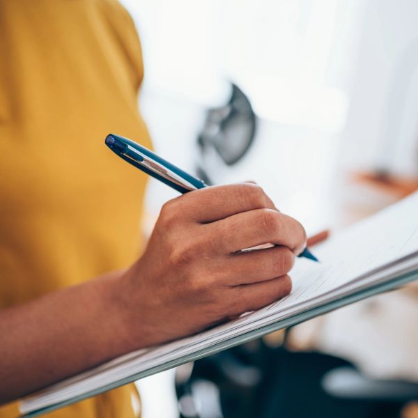 Person writing with a pen on paper.