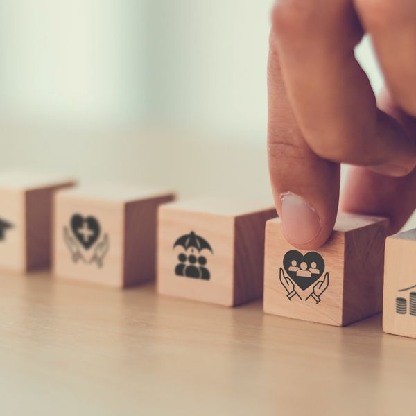 Hand arranging wooden blocks with social and healthcare icons.