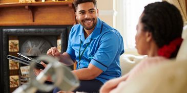 A smiling male nurse consulting with a female patient in a cozy home setting.