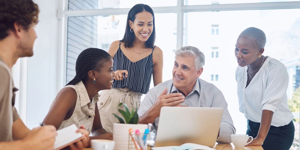 Team discussing ideas around a laptop in an office.