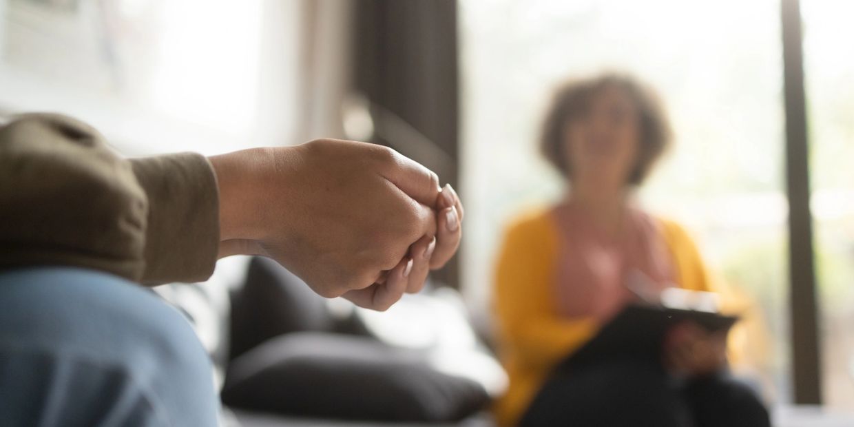 Person nervously clasping hands during a counseling session.