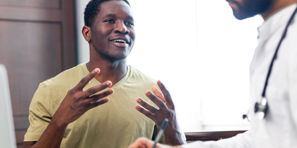 A man enthusiastically talks to a doctor during a consultation.