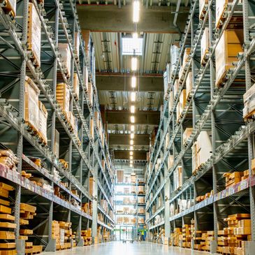 Wide aisle in a large, organized warehouse with tall shelves and boxes.