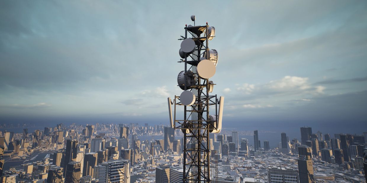 Telecommunication tower over a cityscape under cloudy skies.