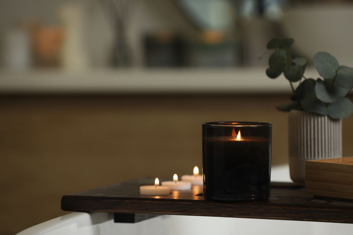 Lit candles on a wooden tray beside a bathtub, creating a cozy atmosphere.