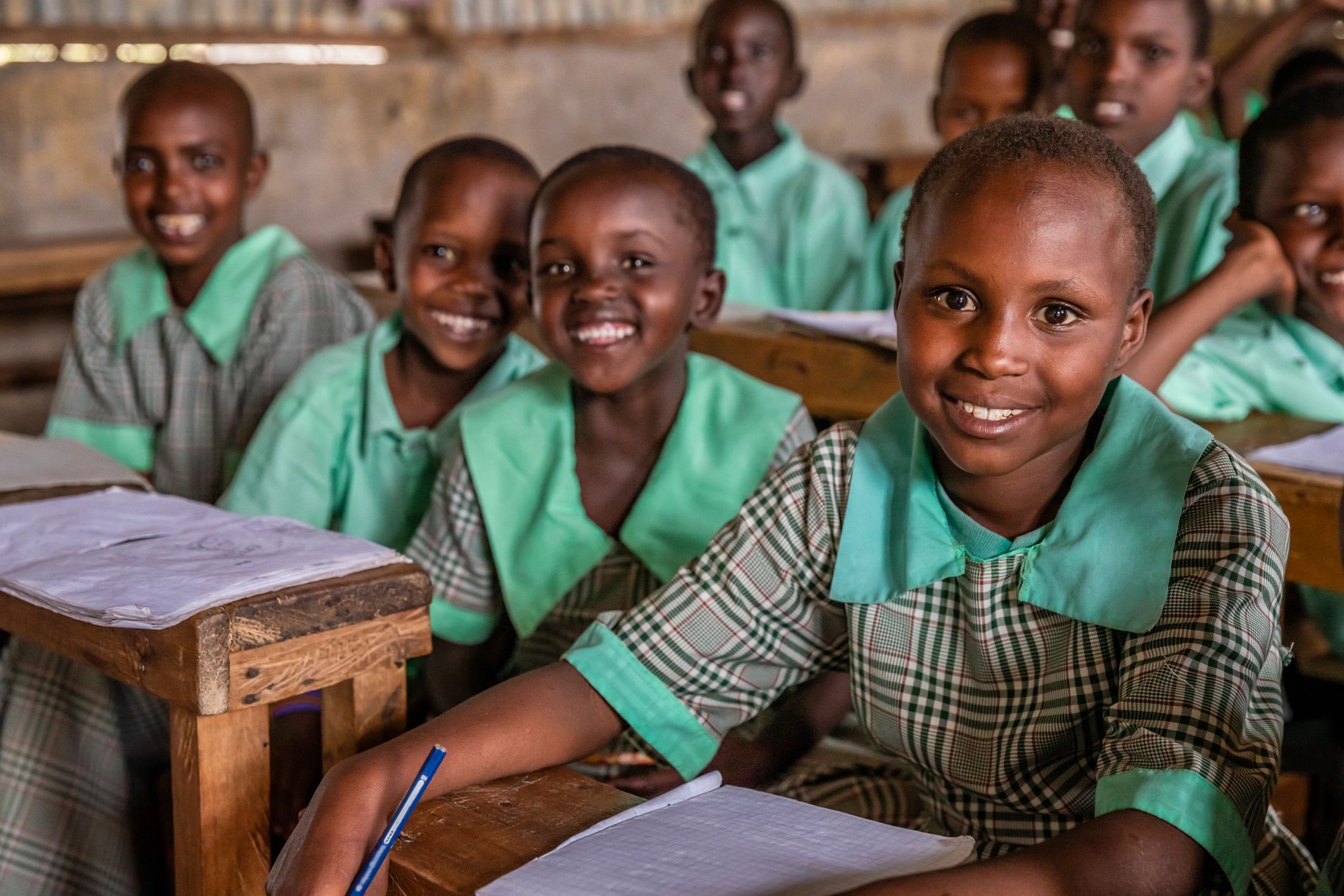 Smiling children in school uniforms sitting at desks.