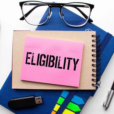 Sticky note with the word 'ELIGIBILITY' on notebooks and office supplies.