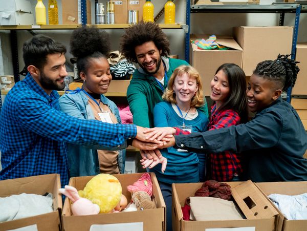 Diverse team hands stacked over boxes.