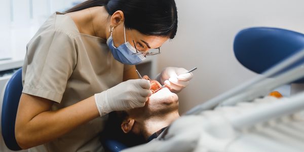 Dentist cleaning inside of patient mouth.