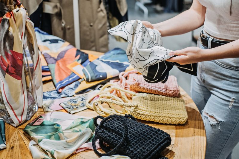 Sustainable fashion. Modern Latina young woman choosing vintage scarf, second hand accessories in vintage shop in shopping mall