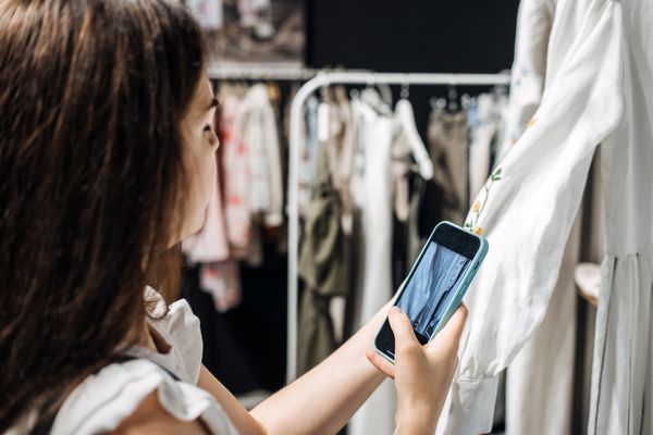 Person taking a photo of clothing with a smartphone, showcasing fashion items for resale..
