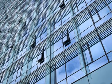 Modern glass building facade with open windows and reflective surfaces.