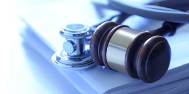 A gavel and stethoscope on a stack of papers representing medical law.