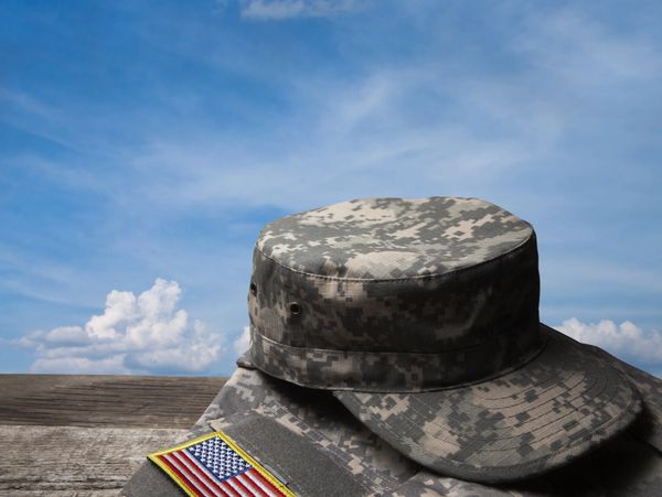 US military uniform and cap with flag patch under blue sky.