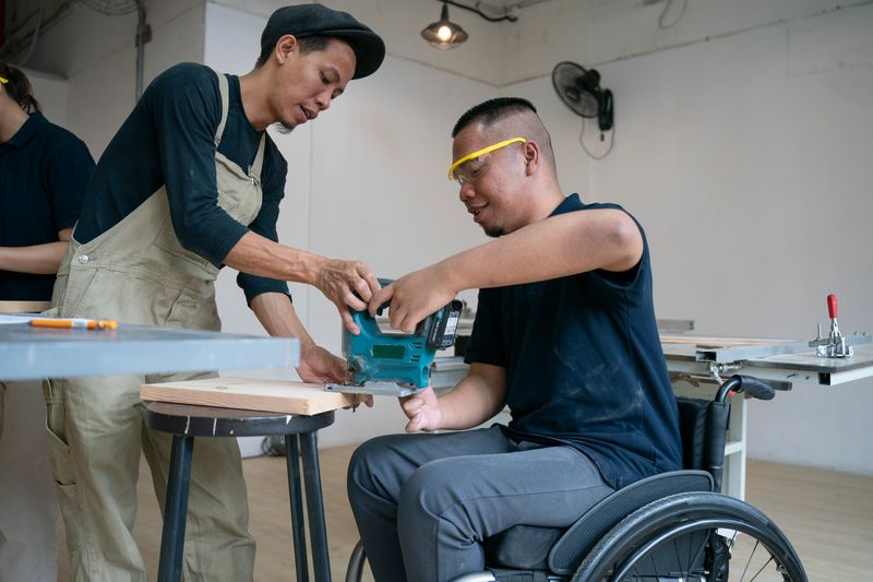 Instructor with a student in a wheelchair during a carpentry workshop
