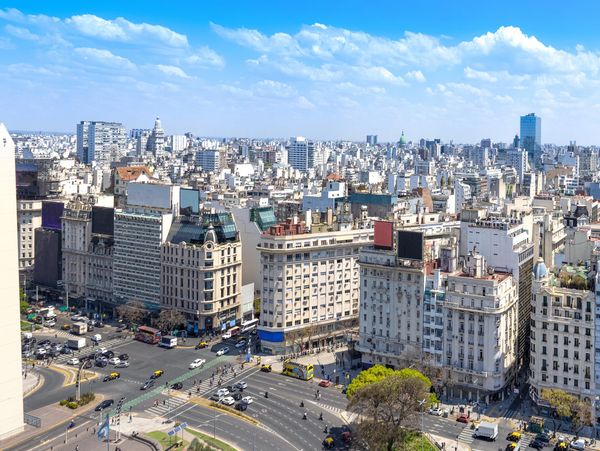 Cityscape with historic buildings and busy streets under a blue sky.