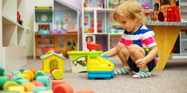 Toddler playing with toy blocks on the floor.