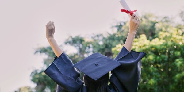 Graduate celebrating with diploma raised in the air.