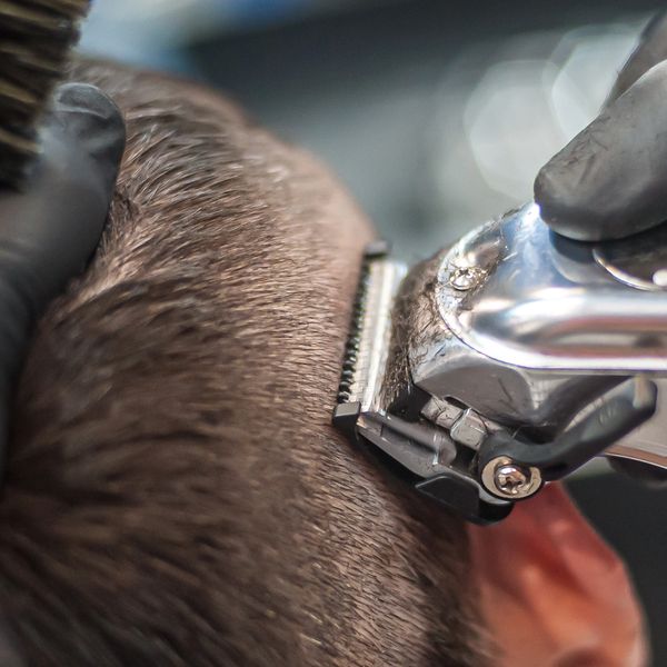 Close-up of a haircut with electric clippers and a brush.