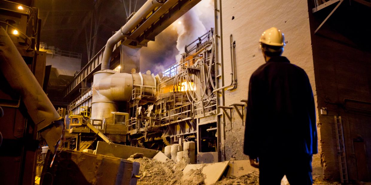 Industrial worker observing furnace operations in a factory.