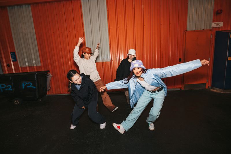Group of four urban style professional dancers dressed with street-style clothes performing in the city streets in New York.